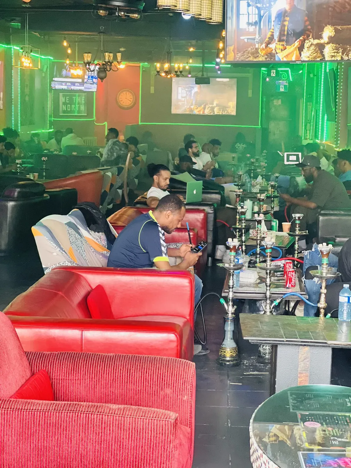 A busy evening at Dose Shisha — guests across the lounge, hookahs on the tables and the We The North sign on the wall